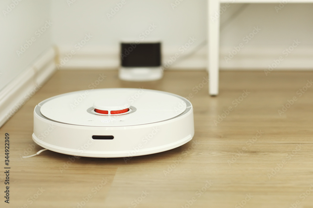 white robotic vacuum cleaner. The robot is controlled by voice commands for direct cleaning. Modern technology of smart cleaning. scheduled cleaning of the apartment. selective focus white robotic vacuum cleaner. The robot is controlled by voice commands for direct cleaning. Modern technology of smart cleaning. scheduled cleaning of the apartment. selective focus