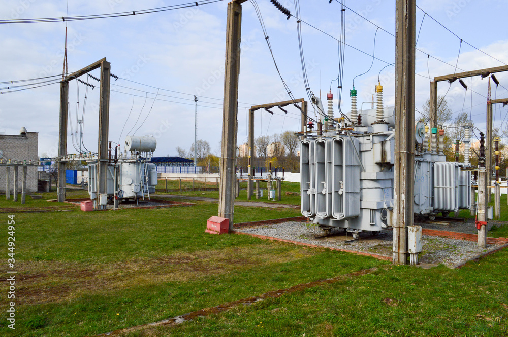 Large industrial iron metal transformer substation with transformers and high-voltage electrical equipment and wires with surge arresters to supply the city with electricity