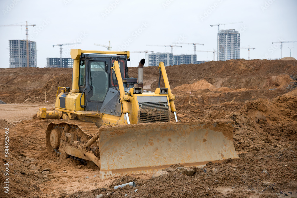 Track-type dozer for pool excavation and utility trenching. Bulldozer during land clearing and foundation digging. Earth-moving heavy equipment at construction site. Digger for road construction