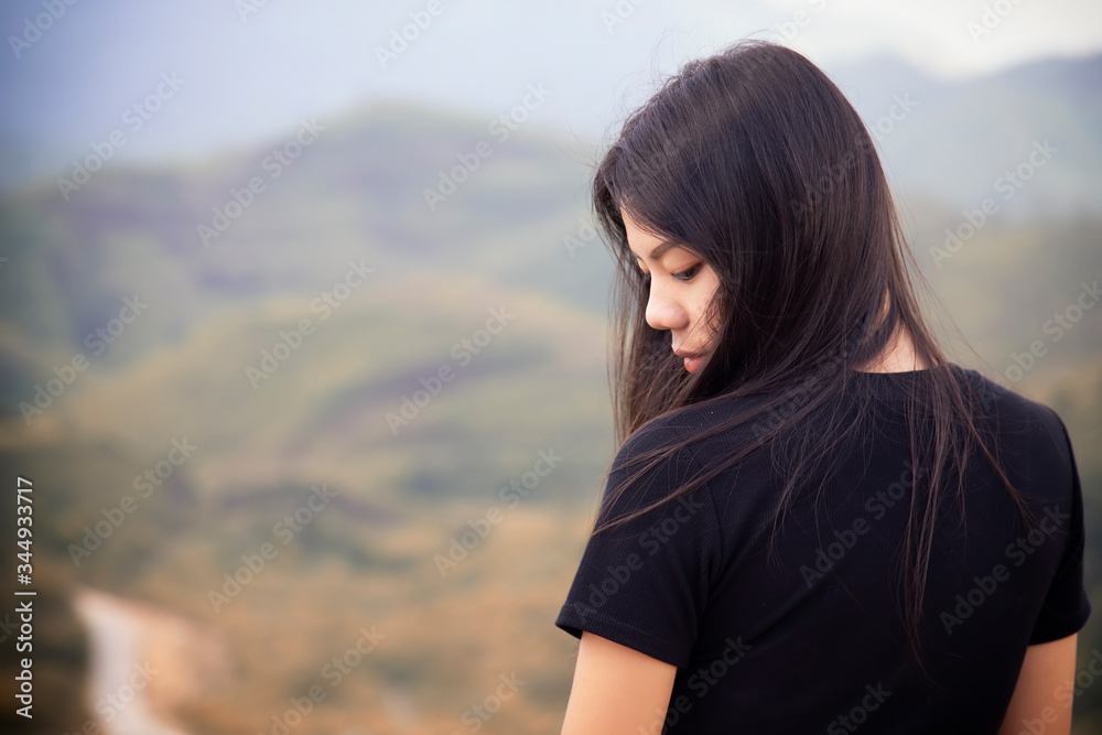 Portrait of asian girl are standing on the moutain to watch the sunset with blurred of green background. Beautiful asian women in black shirt is sad. Portrait of asian girl are standing on the moutain to watch the sunset with blurred of green background. Beautiful asian women in black shirt is sad.