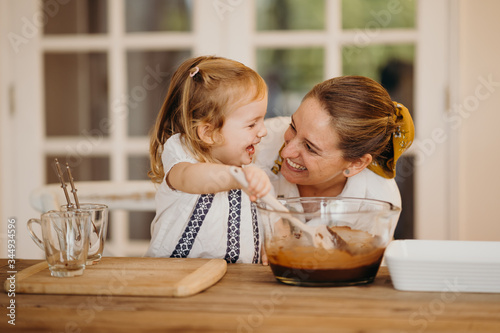 Loving beautiful mother and daughter cooking together a chocolate brownie and having fun