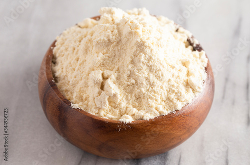 Bowl of Millet Flour in a Wood Bowl on a White Marble Countertop