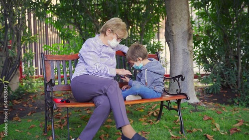 Grandmother playing games with her grandson in the back garden and wearing protective masks