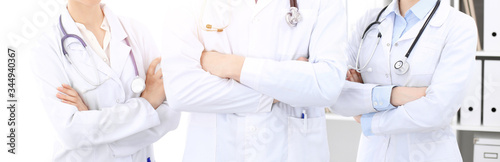 Unknown woman-doctor standing straight with arms crossed in clinic, close-up. Medical team ready to stop coronavirus pandemic. Medicine concept