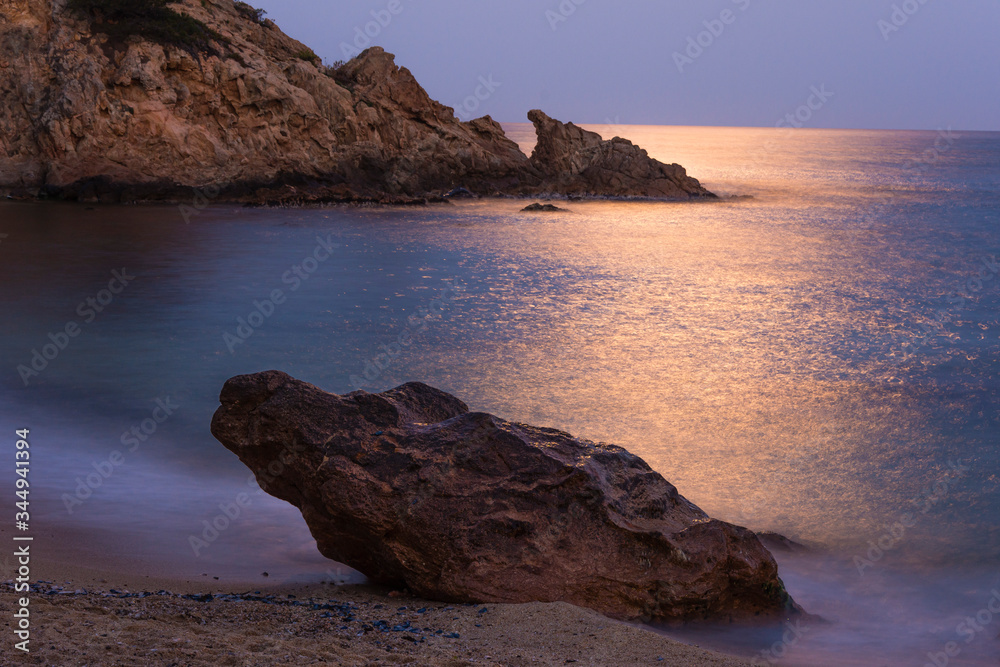 Beach with rocks with reflection of light in the sea