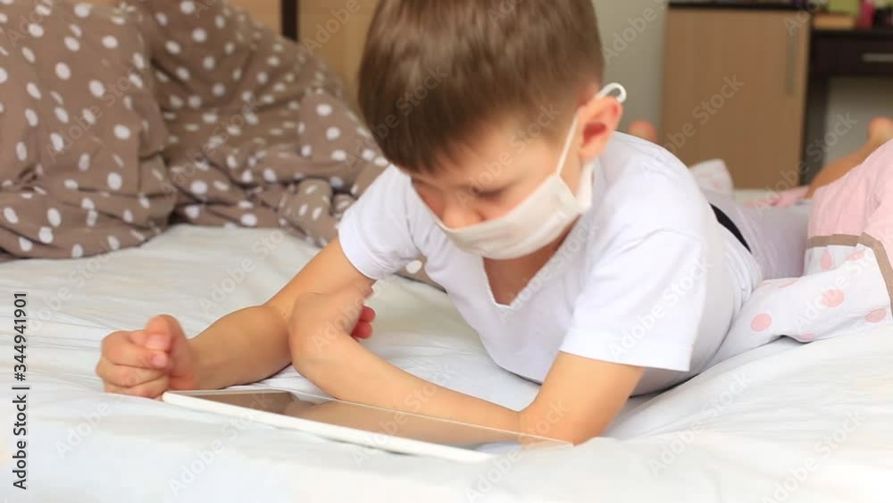 Boy puts on a quarantine respiratory mask at home see in tablet Boy puts on a quarantine respiratory mask at home see in tablet