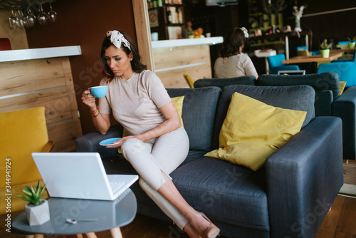 Attractive young caucasian woman drinking coffee and working on laptop. Business and pleasure