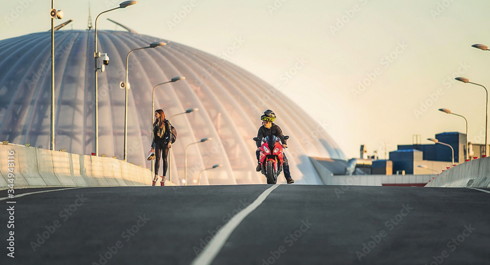 Man riding red bike looking at woman walking on the bridge on sunrise