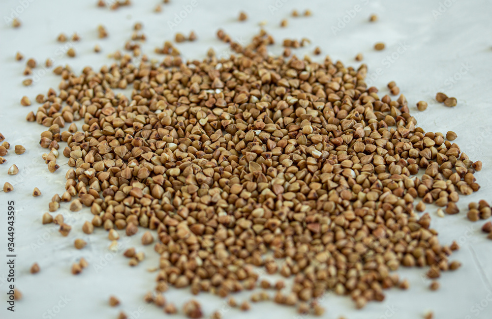 Buckwheat groats closeup scattered on a light gray table Buckwheat groats closeup scattered on a light gray table