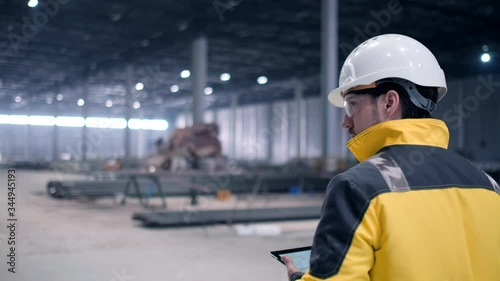 Follow footage of employees male warehouse worker engineer in hard hat working. walking through logistics center warehouse factory construction site logistics architect businessman man builder indoors