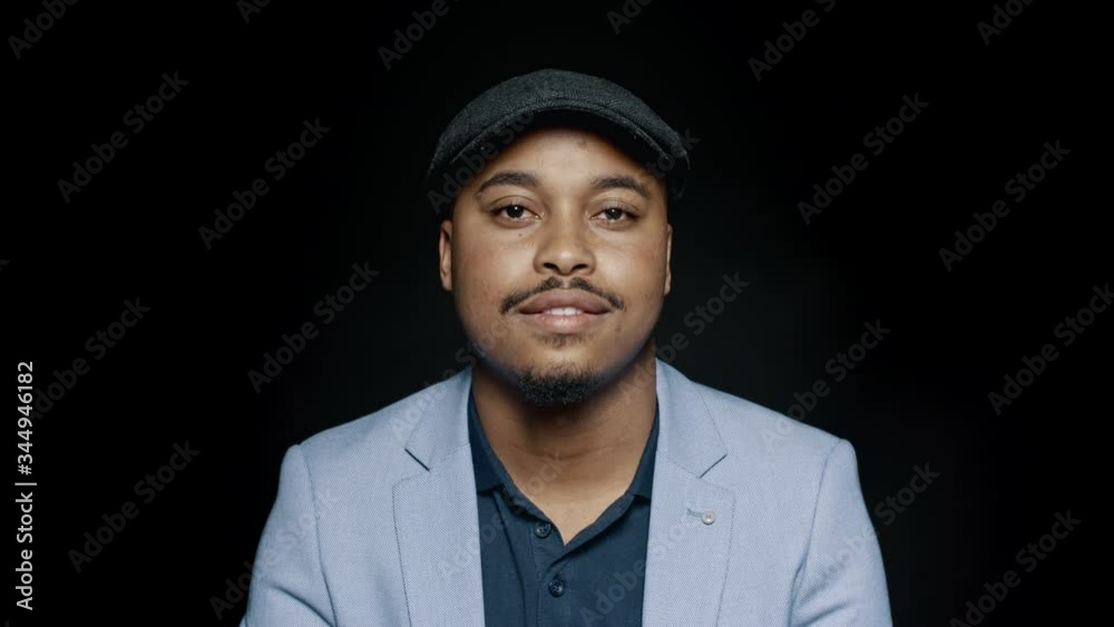Close up of an african american businessman in a cap isolated on black background. Man wearing a suit and cap looking at camera.
Close up of an african american businessman in a cap isolated on black background. Man wearing a suit and cap looking at camera.