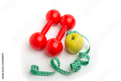 Bright apple and red dumbbells with a Measuring tape on a white background