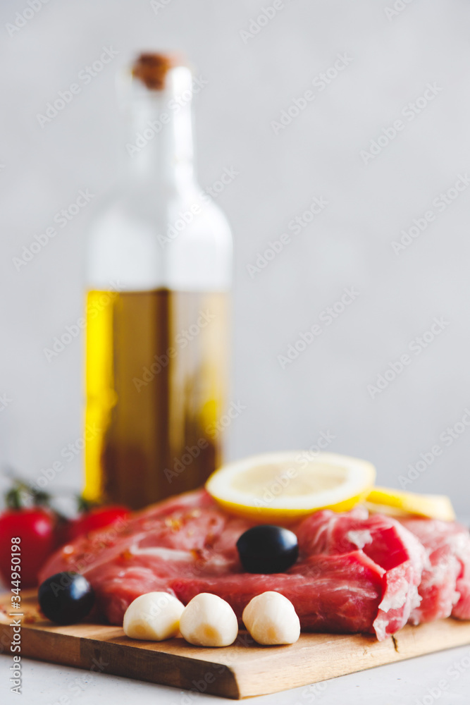 A close-up of pork steaks marinated in spices, with olives and lemon on them. Vertical orientation. Grilling meat A close-up of pork steaks marinated in spices, with olives and lemon on them. Vertical orientation. Grilling meat