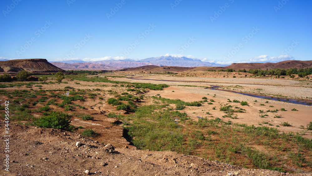 Rural landscape in Morocco with a river heading to the Atlas mountains on background