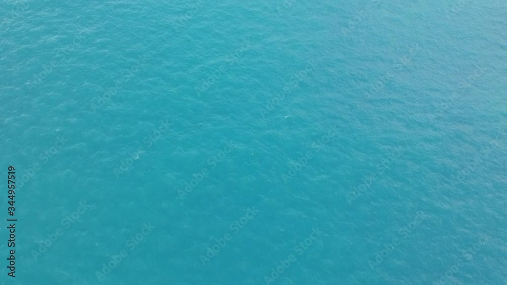 flying over the blue water of the ocean and the sea without waves flying over the blue water of the ocean and the sea without waves