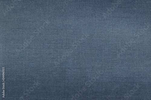 Grunge texture of natural blue denim frayed fabric. Abstract monochrome background of beautiful classic denim.