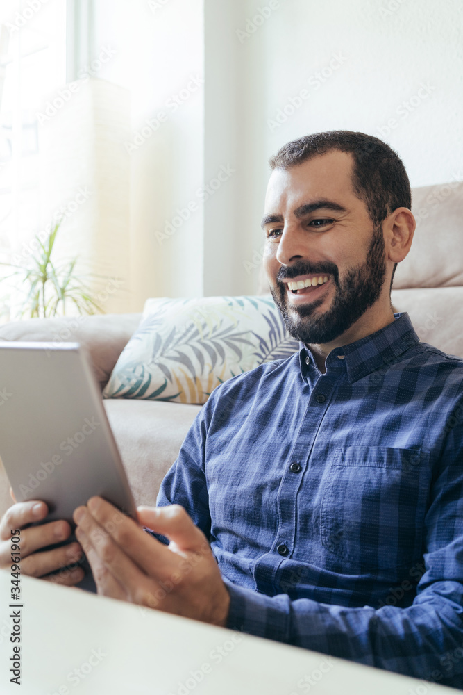 Happy young man sitting on floor and using digital tablet at home. Happy young man sitting on floor and using digital tablet at home.