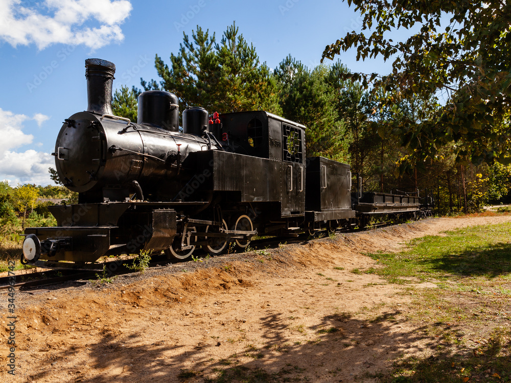 Antique train. Narrow-gauge railway. Black metal locomotive in Topilo village, podlasie, Poland. Sunny vacation day. Antique train. Narrow-gauge railway. Black metal locomotive in Topilo village, podlasie, Poland. Sunny vacation day.
