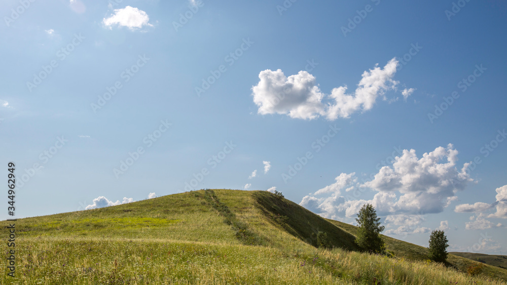 top of a green hill against a blue sky with rare clouds