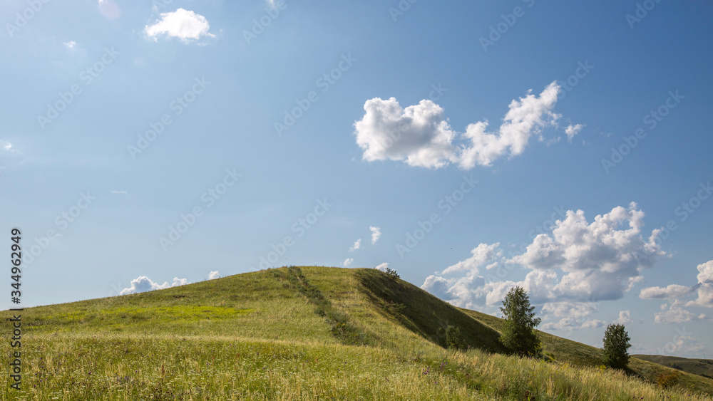 Fototapeta premium top of a green hill against a blue sky with rare clouds