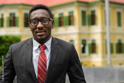 Happy young African businessman with eyeglasses smiling in the city streets outdoors