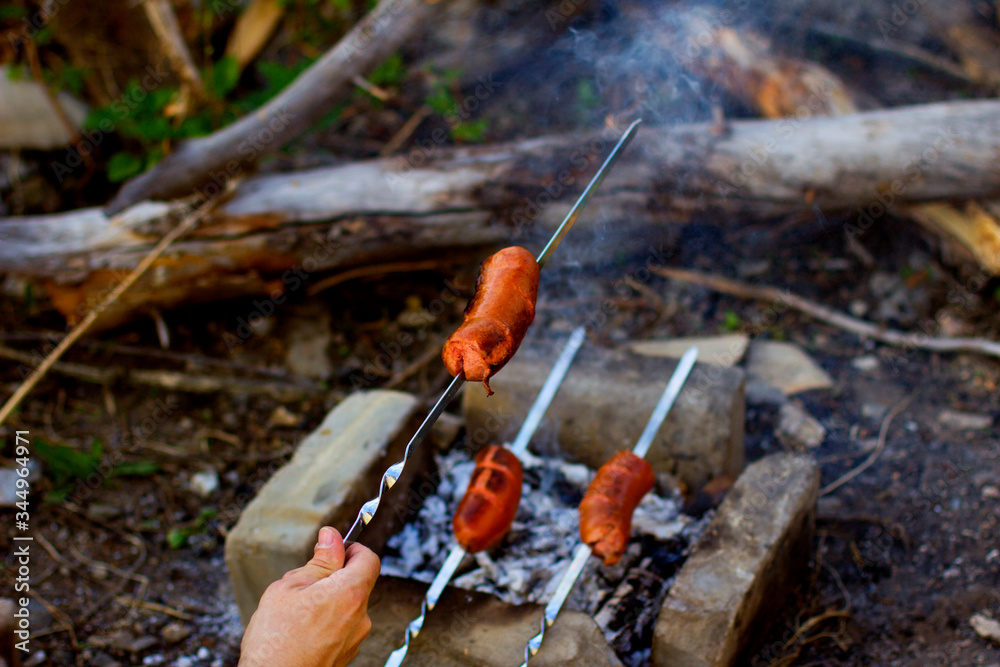 Sausages are grilled on skewers on hot coals, tasty street food sold at a meat barbecue, camping, picnic. Barbecue in the garden. Sausages are grilled on skewers on hot coals, tasty street food sold at a meat barbecue, camping, picnic. Barbecue in the garden.