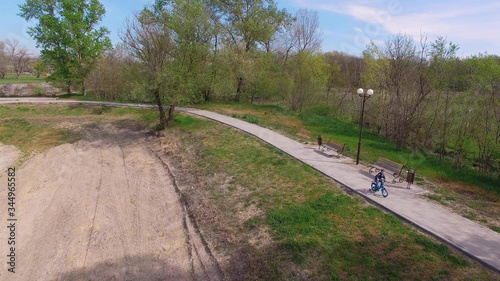 the kid rides to the Park on a blue bike with side wheels