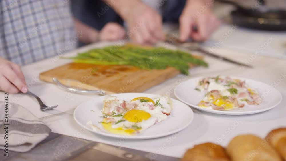 Mid-section shot of hands of unrecognizable man giving fork to little son and picking up plates with fried eggs Mid-section shot of hands of unrecognizable man giving fork to little son and picking up plates with fried eggs
