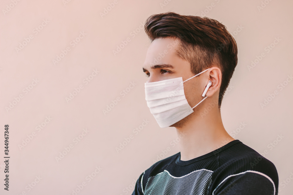 oosten hypothese Intensief Portrait young confident fitness trainer in protective mask listening music  with wireless earbuds. Happy sports man in medical face mask at home  quarantine. Motivation, COVID-19 coronavirus protection Stock 写真 | Adobe  Stock