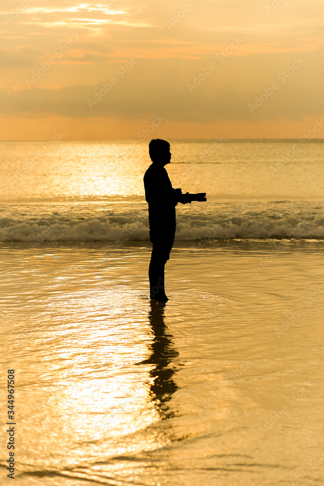 Man photographer act shooting with landscape sea sunset background