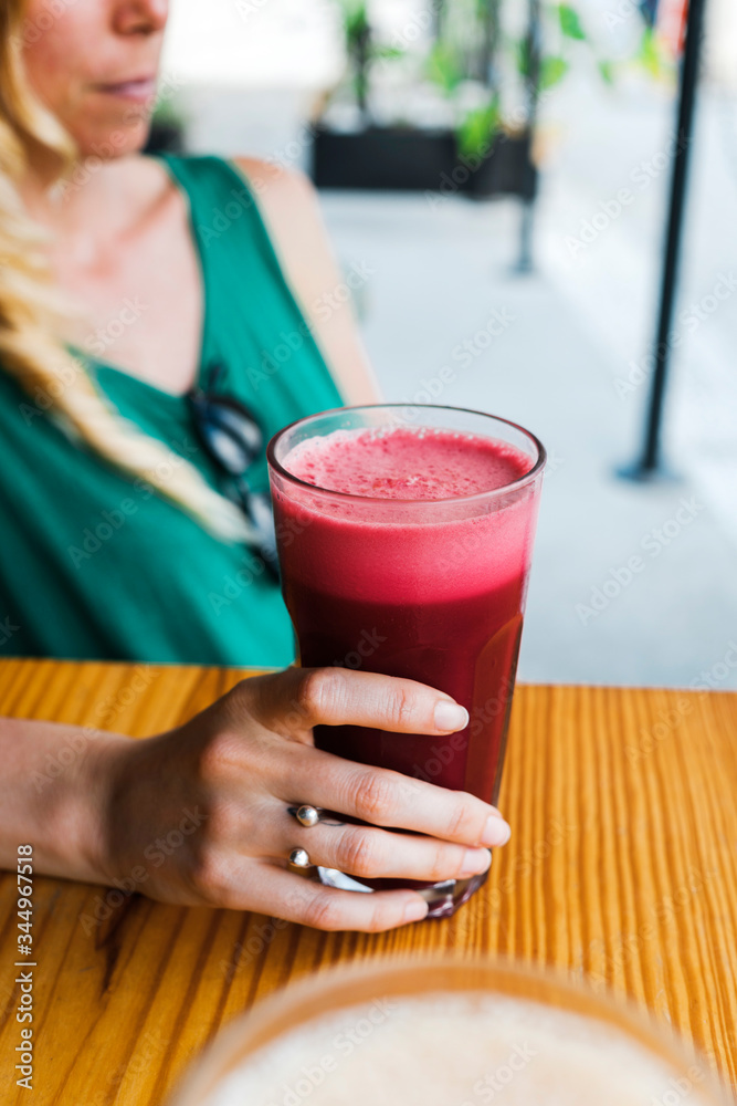 Close up of woman hand holding fresh juice in cafe