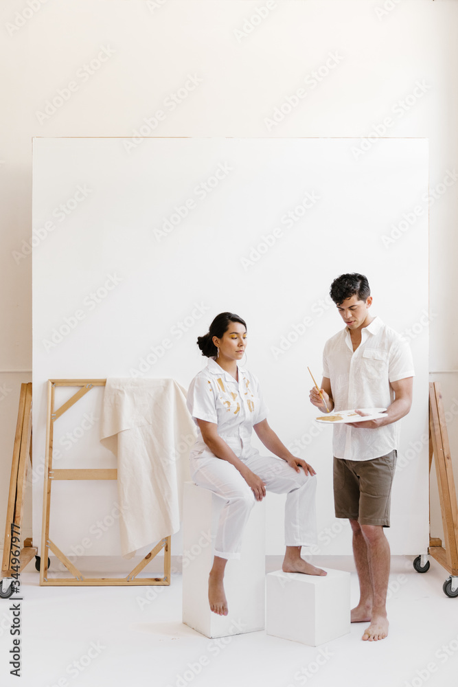 young man painting on woman wearing white in photo studio young man painting on woman wearing white in photo studio