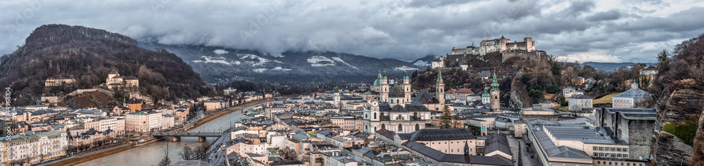 Panoramic view of Salzburg old town skyline with Fortress on the hill and Salzach river in overcast days