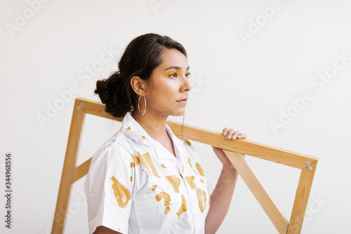 young woman with painted shirt holding painter's canvas frame photo