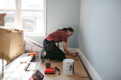 Young woman painting house trim inside.