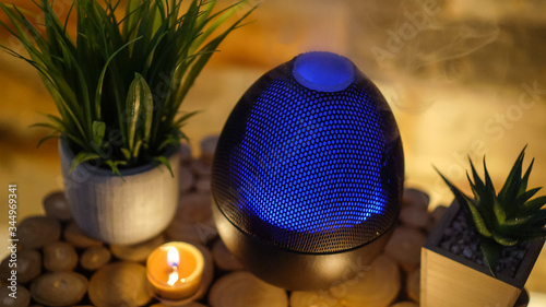 Electric oil diffuser lamp, candles on wooden table in room.