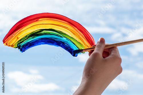 Close-up of a hand with a brush paints a rainbow, end of quarantine, self-isolation, support of doctors, stay at home, flash mob photo