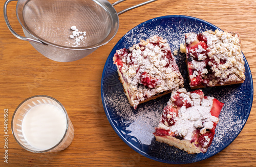 yeast strawberry cake, covered with powder sugar, with glass of milk