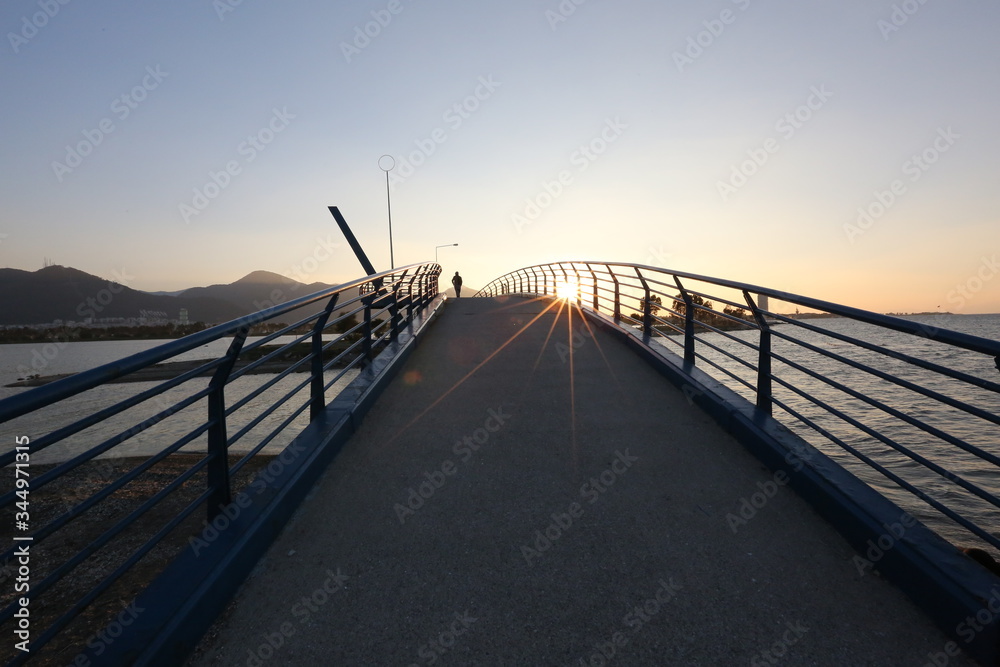 sunset, people walking on the bridge, sea, mountain, sun