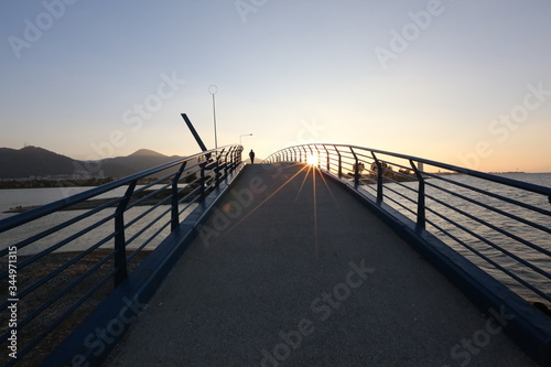 sunset, people walking on the bridge, sea, mountain, sun © ctrl+s photo