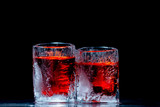 Dos vasos de hielo con licor rojo sobre fondo negro