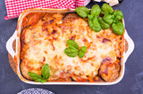 Healthy zucchini lasagna bolognese in a baking dish with olive oil. Oven baked traditional Italian cuisine with mozzarella, parmesan, basil and vegetables. Copy space. Above