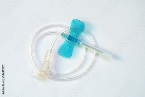 Blue butterfly catheter on light background.  Butterfly dropper needle