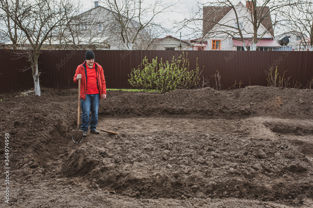A man digs the ground with a shovel in the spring. Pond with his hands. A man digs the ground with a shovel in the spring. Pond with his hands.