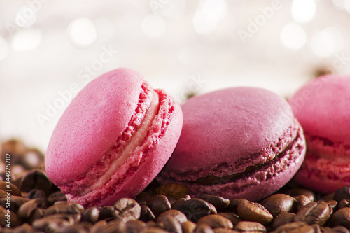 Macaroons on a wooden table with roasted coffee beans in soft light, close-up, tasty cookies. Morning coffee and breakfast.