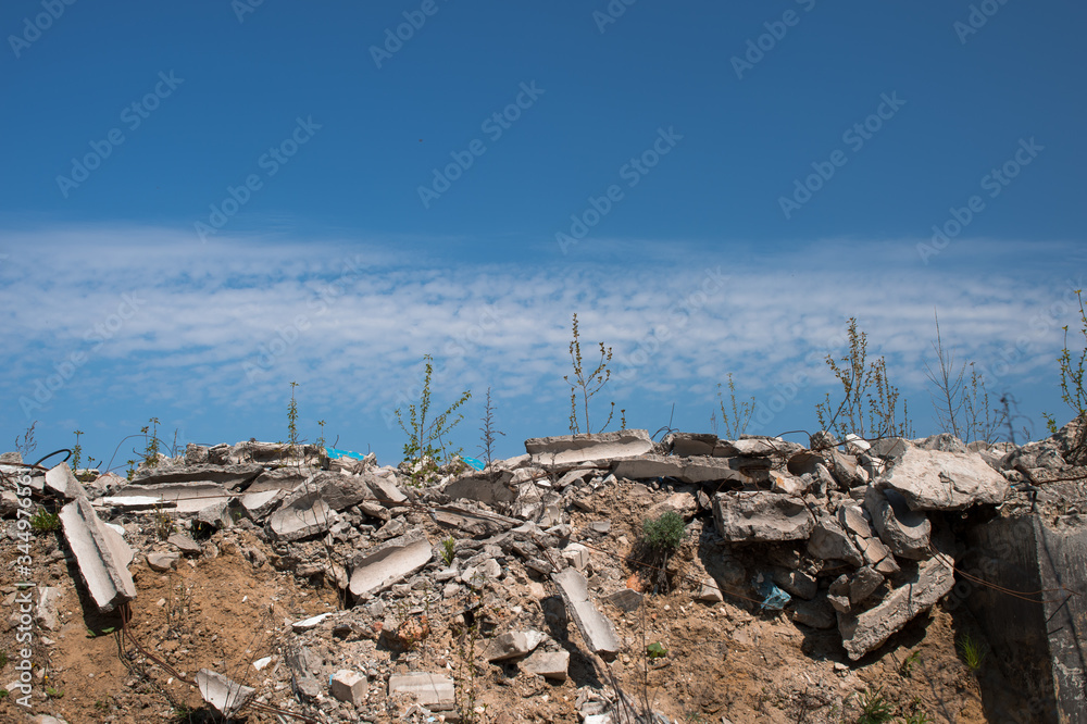 A pile of gray concrete debris against a blue textured sky with feathery white clouds. Background