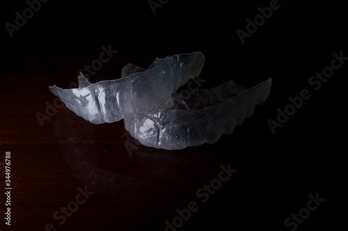 clear individual tooth tray for whitening, mouth to protect from grinding caused by bruxism, invisible Orthodontic Retainers - Concept photo with dramatic light, copy space and black background