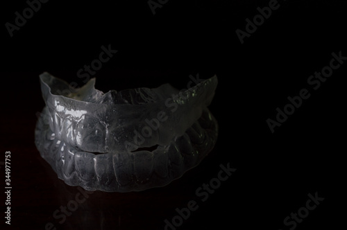 clear individual tooth tray for whitening, mouth to protect from grinding caused by bruxism, invisible Orthodontic Retainers - Concept photo with dramatic light, copy space and black background