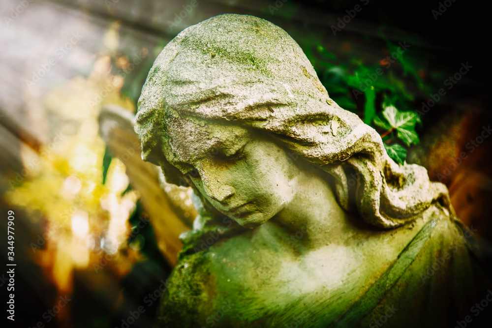 Obraz premium Antique statue of wonderful angel in the rays of the sun on green background. Architecture, sculpture, religion, faith concept.