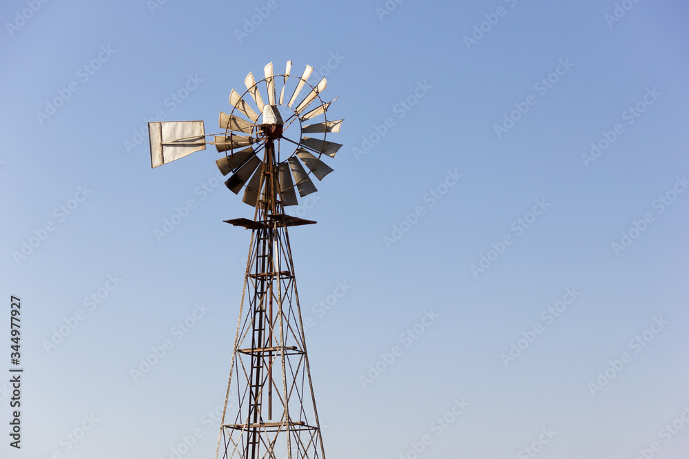 Rusty metal windmill at sunset over blue sky background. Agrarian classic building structure in Fuerteventura island, Spain. Remote location, vintage, old fashioned concepts Rusty metal windmill at sunset over blue sky background. Agrarian classic building structure in Fuerteventura island, Spain. Remote location, vintage, old fashioned concepts